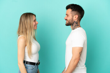 Young couple over isolated blue background looking at each other