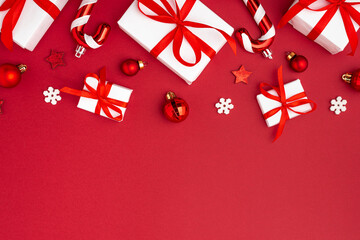 Christmas composition on red background. White gift boxes with Christmas decorations. Top view. Flat lay