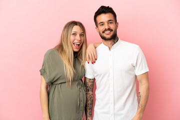 Pregnant woman and man over isolated pink background happy and laughing