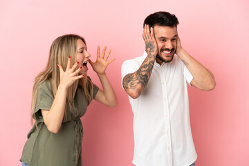 Pregnant woman and man over isolated pink background frustrated and shouting