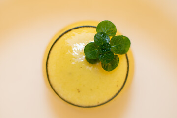 Vaso con jugo de maracuyá y plantita verde en plano cenital