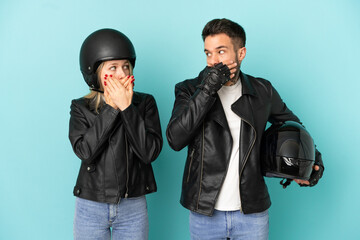 Couple with motorcycle helmet over isolated blue background covering mouth with hands for saying something inappropriate - obrazy, fototapety, plakaty
