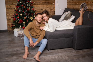 Obraz premium woman enjoying time together with her boyfriend at home. Christmas tree on background.
