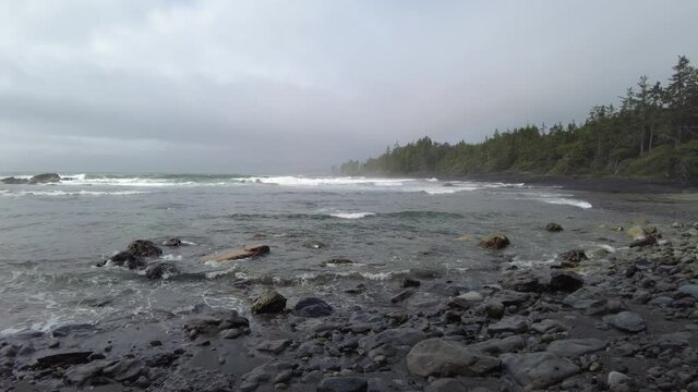 Big waves on the pacific side of Vancouver Island. Stormy cold ocean a wild stony beach surrounded by the forest. 
