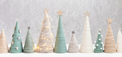 Christmas craft background with handmade yarn cone xmas trees in natural colors.  DIY organic sustainable christmas decoration