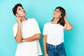 Young mixed race couple isolated on blue background thinking an idea while scratching head
