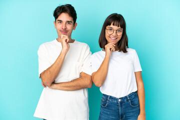 Young mixed race couple isolated on blue background smiling with a sweet expression