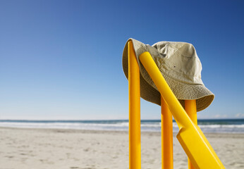 Sunhat and bat resting on yellow cricket stumps at the beach