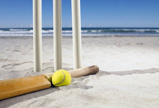 Bat and ball laying beside cricket stumps at the beach