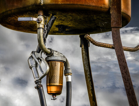 Old farm gasoline pump against stormy sky