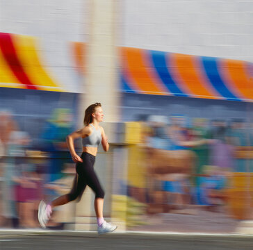Young woman running along street in front of mural