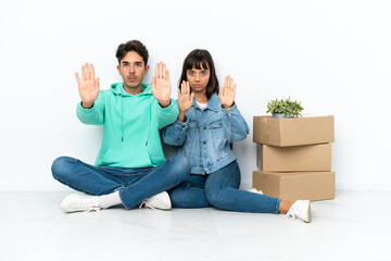 Young couple making a move while picking up a box full of things sitting on the floor isolated on...