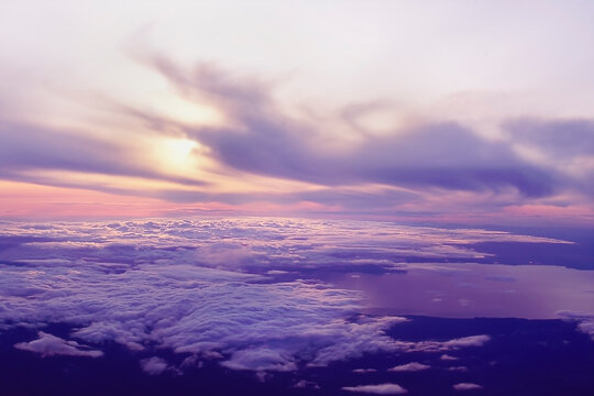 Looking down at top of clouds and sun setting