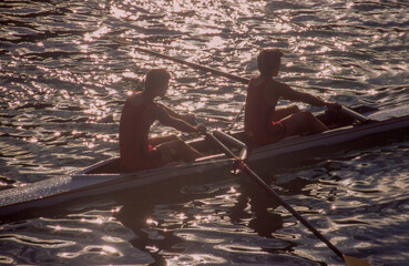 Two men rowing in double scull on water