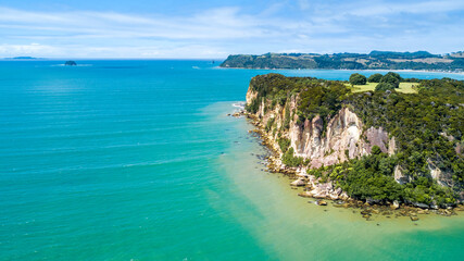 Fototapeta na wymiar Aerial view on a rocky cliff with a beautiful harbour on the background. Coromandel, New Zealand.