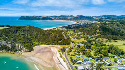 Beautiful beach with a little village on the background. Coromandel, New Zealand.