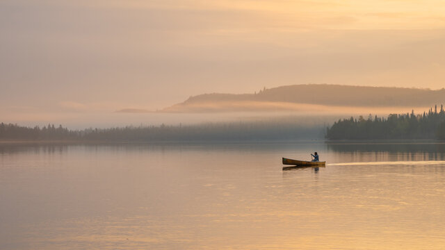 People are boating on Caribou Lake on a fogy morning