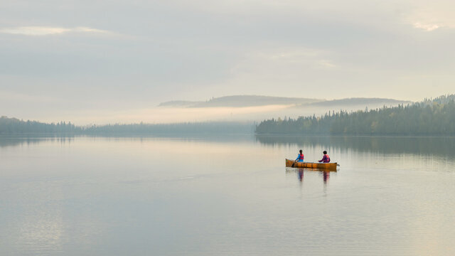 People are boating on Caribou Lake on a fogy morning