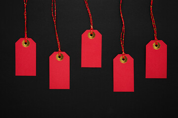 Red sale tags on a black background. Discounts and Black Friday concept. Top view, copy space
