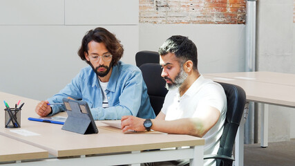 Two men working as a team in an office or coworking with a laptop