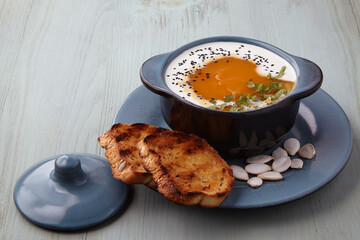 Pumpkin cream soup with cream, black cumin seeds, herbs and toasted bread