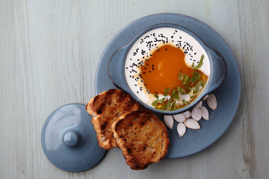 Pumpkin cream soup with cream, black cumin seeds, herbs and toasted bread