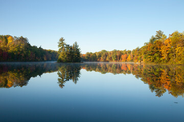 Beautiful lake with trees in autumn color and a small island in northern Minnesota on a calm clear...