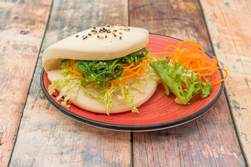 Vegetable sandwich of Japanese bao bread with wakame seaweed salad, lettuce and grated carrot with sesame seeds and poppy