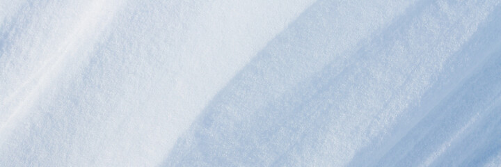 Obraz premium Beautiful winter background with snowy ground. Natural snow texture. Wind sculpted patterns on snow surface. Wide panoramic texture for background and design.