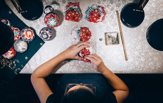 top view of a woman in a workshop making handmade Christmas ornaments.
