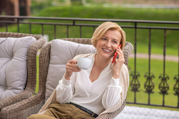 Cheerful blonde female calling on her cellphone on the terrace