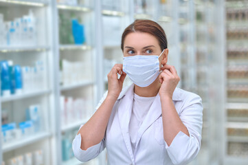 Confident woman in lab coat and protective mask