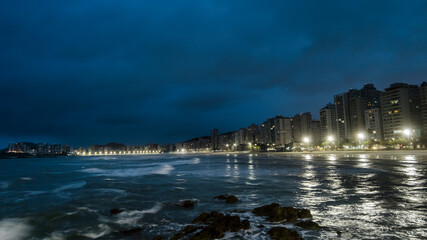Night view of sea rocks with the background of Pitangueiras Beach with avenue and rise apartments...