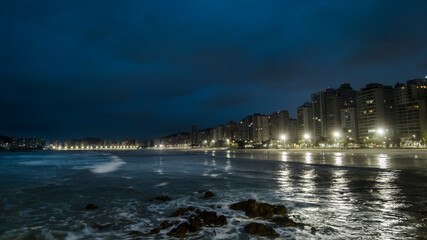 Night view of sea rocks with the background of Pitangueiras Beach with avenue and rise apartments...