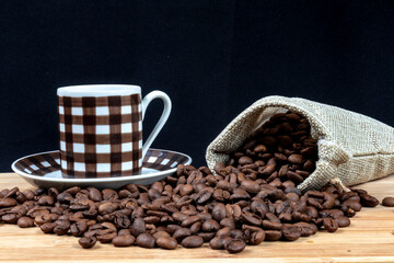 cup of coffee, roasted coffee beans and little jute bag in wooden table in Brazil