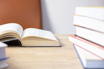 Close up and selective focus photo of science textbook opening page and stacks of many books as foreground and beautiful sunlight from window with nobody shows concept of studying and education.