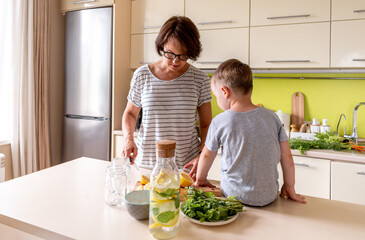 Adult woman is preparing lemonade with her son. Cold drink. Summer heat. Vegetarian food concept.