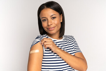 Happy african american woman look at adhesive plaster on shoulder after getting coronavirus...