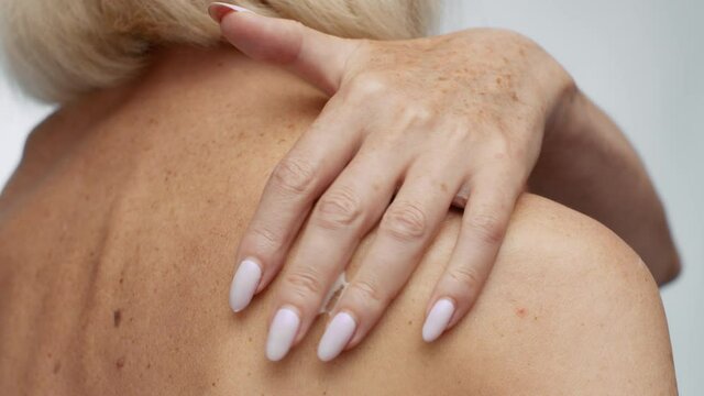 Senior body care. Close up shot of unrecognizable mature lady applying pampering cream on her bare shoulder