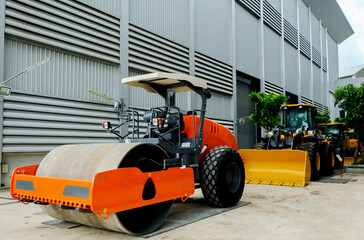 An orange road roller is parked in the company.