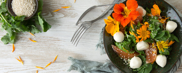 flat lay of salad bowl with arugula, grapefruit, mozzarella and edible marigold and nasturtium...