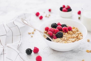 Breakfast bowl with granola, muesli, raspberry, blackberry on gray table