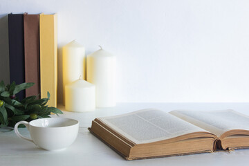 An old books with white candles and coffee cup with nature light. 