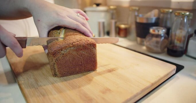 woman hands cutting slices fresh homemade baked loaf of banana bread cake with nuts bakery on wooden board at the kitchen