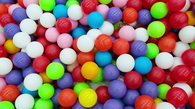 Blonde toddler boy lying on multi coloured plastic balls in big dry paddling pool in playing centre. Looking at camera. Having fun in playroom. Leisure Activity. Portrait close up.