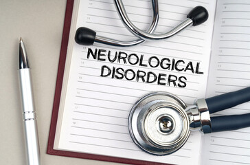 On the table is a stethoscope, a pen and a notebook in which it is written - Neurological Disorders