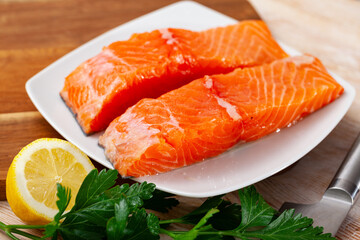 Image of appetizing raw salmon fillet with lemon and greens before cooking