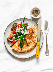 Oatmeal crepes without flour with asparagus, feta, cherry tomatoes - delicious diet breakfast on a dark background, top view