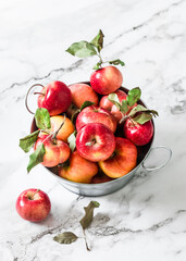 Autumn red ripe apples in a metal basket on a marble background, top view