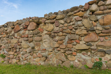 An old medieval stone wall against blue sky as background